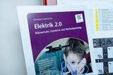 Produktbilder vom Experimentierkoffer Elektrik "Induktion und Wechselspannung", Einblick in den Experimentierkoffer und in die Lehrerhandreichung, sowie in die Versuchsmaterialien und -aufbauten