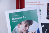 Das Bild zeigt ein Demonstrationsset mit dem Titel „Dynamik 2.0“ für den Unterricht, das Teil des Cornelsen Experimenta Programms ist. Im Hintergrund sind weitere Materialien und Werkzeuge zu sehen, die für experimentelle Lehrmethoden verwendet werden.