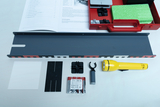 Das Bild zeigt eine Sammlung von Experimentiermaterialien, darunter eine graue Schiene, eine Taschenlampe, Batterien und verschiedene kleine Komponenten. Zusätzlich liegt ein Handbuch mit Anleitungen zur Durchführung von Experimenten dabei.