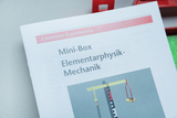 Das Bild zeigt eine Anleitung für eine Mini-Box, die für Experimente in der Elementarphysik und Mechanik gedacht ist. Auf der Seite wird ein Experimentieraufbau mit verschiedenen Komponenten dargestellt, um physikalische Konzepte zu veranschaulichen.