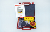 Das Bild zeigt eine rotfarbene Box für Experimentierbedarf, die eine Mini-Box für Elementarphysik mit verschiedenen Materialien enthält. Dazu gehören unter anderem Röhren, Saiten und eine Anleitung zur Durchführung von Klangexperimenten.