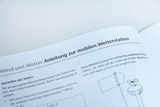 Das Bild zeigt eine Anleitung zur mobilen Wetterstation, die in einem Bildungsumfeld verwendet wird. Die Anleitung beschreibt, wie der Stativ richtig aufgestellt werden kann und gibt Hinweise zur Anpassung an die Größe der Kinder.