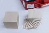 Das Bild zeigt einen großen Würfel und eine gestapelte Anordnung von dünnen quadratischen Platten in beige, die aus einem speziellen Material bestehen. Diese Materialien sind Teil eines Lehrer- und Schülerexperimentierkits zur Veranschaulichung mathematis