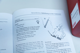 Das Bild zeigt eine Anleitung für ein Experiment namens „Das Roboterspiel“, das in einem Lehrbuch zur Elektronik steht. Es enthält eine Liste der benötigten Materialien und eine kurze Bauanleitung für ein einfaches elektromagnetisches Gerät.