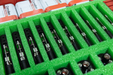 Das Bild zeigt eine Reihe von experimentellen Messinstrumenten, die in einem grünen, schaumstoffgepolsterten Behälter angeordnet sind. Im Hintergrund sind mehrere Batterien sichtbar, die für die Geräte verwendet werden können.