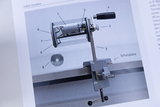 Das Bild zeigt ein mechanisches Gerät, das als DynaMot bezeichnet wird, und ist für experimentelle Anwendungen im Bildungsbereich gedacht. Es ist in einem klaren Gehäuse untergebracht und konzentriert sich auf die Darstellung verschiedener Teile wie Motor
