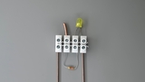 Das Bild zeigt eine elektronische Schaltung, bestehend aus einer LED, einer Widerstand und einem Verbindungselement für Drähte. Die Anordnung ist ideal für Experimente im Bildungsbereich, um grundlegende Kenntnisse der Elektrotechnik zu vermitteln.