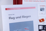 Das Bild zeigt eine Anleitung für ein Experimentier-Set mit dem Titel "Flug und Fliegen", das von Cornelsen Experimenta angeboten wird. Es dient als Demo-Set für den Unterricht im deutschen Bildungswesen und bietet praktische Experimente zum Thema Flug.