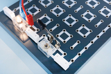 Das Bild zeigt ein Experimentierboard mit sichtbaren elektrischen Verbindungen, darauf befinden sich eine glühende Lampe und ein Schalter. Die Anordnung ist optimiert für die Durchführung von elektrischen Experimenten im Bildungsbereich.
