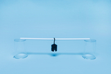 Das Bild zeigt ein einfaches Experimentier-Setup bestehend aus zwei durchsichtigen Bechern, einem weißen Rohr und einem daran hängenden Gewicht. Dieses Arrangement dient wahrscheinlich dazu, Grundlagen der Physik, wie das Gleichgewicht von Kräften, zu demonstrieren.