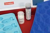 Das Bild zeigt eine blaue Silikonform mit verschiedenen Formen sowie zwei Behälter: einen für Zucker und einen mit roter Lebensmittelfarbe (E 129). Diese Materialien sind Teil eines Experimentiersets für den Bildungsbereich von Cornelsen.