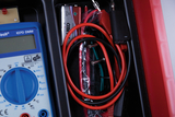 Das Bild zeigt ein Multimeter mit verschiedenen Anschlusskabeln und einer 9-Volt-Batterie. Diese Ausrüstung ist typischerweise für Experimente und Messungen im Bildungsbereich konzipiert.