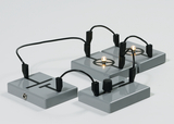 Das Bild zeigt eine Experimentieranordnung mit mehreren grauen Bausteinen, die durch Kabel verbunden sind. Einige dieser Bausteine sind mit Lampen ausgestattet, die eine leuchtende Funktion demonstrieren.