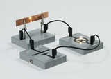 Das Bild zeigt ein Experimentier-Set mit zwei grauen Plattformen, die elektrische Kontakte und eine Glühbirne enthalten. Eine Metallplatte ist mit Klemmen verbunden, um Strom zu leiten und physikalische Prinzipien zu demonstrieren.