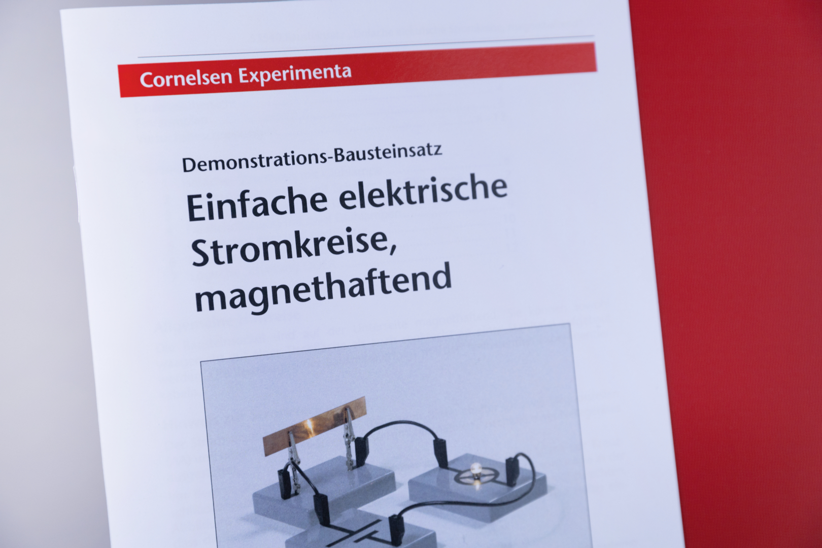 Das Bild zeigt eine Anleitung für ein Experiment mit einfachen elektrischen Stromkreisen, die magnethaftend sind. Es vermittelt Informationen zu einem Demonstrationsbausatz aus dem Bildungsbereich von Cornelsen Experimenta.