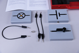 Das Bild zeigt verschiedene Experimentierkomponenten, darunter Schaltkästchen mit verschiedenen Symbolen, Verbindungskabel und eine Glühbirne. Diese Materialien sind für educational Experimente im Bereich Elektrotechnik konzipiert und bieten praxisnahe Lernmöglichkeiten.