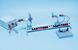 Das Bild zeigt ein experimentelles Gerät mit einem Elektromotor mit Propeller, der auf einer Schiene angebracht ist, sowie einer Stromversorgungseinheit. Das Setup ist deutlich für Bildungszwecke im Bereich Physik ausgestattet und bietet experimentelle Möglichkeiten zur Erkundung von Bewegung und Elektromotorik.