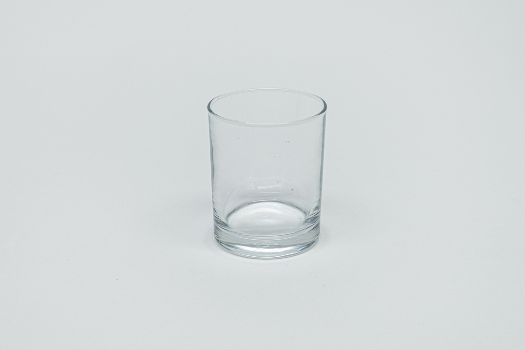 Das Bild zeigt ein transparentes Glas, das in einem neutralen Umfeld fotografiert wurde. Es handelt sich um ein einfaches, zylindrisches Gefäß, das für Experimente im Bildungsbereich verwendet werden kann.