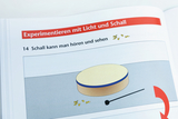 Das Bild zeigt eine Illustration aus einem Lehrbuch über Experimente mit Licht und Schall. Es behandelt die Wahrnehmung von Schall und zeigt eine Abbildung eines Instruments sowie einige Notensymbole.