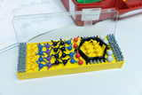 Das Bild zeigt ein molekulares Baukastenset, das aus verschiedenen bunten Kunststoffkugeln und Verbindungselementen besteht. Es liegt auf einem Tisch, umgeben von Unterrichtsmaterialien, und ist für experimentelle Zwecke im Bildungswesen konzipiert.