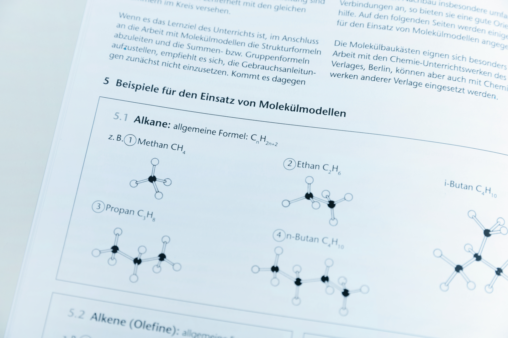 Das Bild zeigt eine Seite aus einem Lehrbuch, die Beispiele für Molekülmodelle von Alkanen beinhaltet. Es sind chemische Strukturformeln für Methan, Ethan, Propan und Butan abgebildet, begleitet von deren allgemeinen Formel und Bezeichnungen.