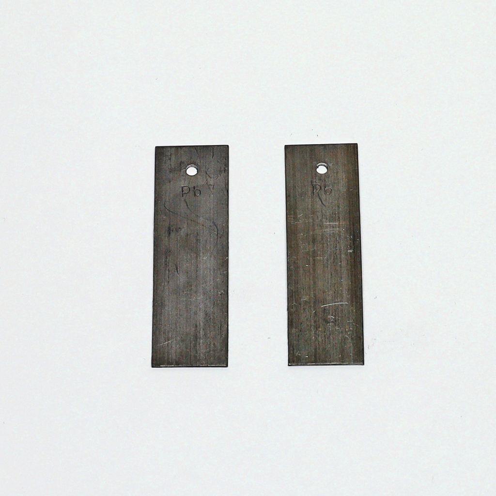 Das Bild zeigt zwei metallene Platten mit Löchern am oberen Ende, die zur Verwendung in Experimenten im Bildungsbereich gedacht sind. Beide Platten sind beschriftet und scheinen aus dem gleichen Material zu bestehen, möglicherweise aus Blei.
