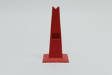 Das Bild zeigt einen roten, pyramidenförmigen Halter mit einer quadratischen Basis und einer Aussparung an der Vorderseite. Dieses Objekt könnte zur Befestigung oder Präsentation von Experimentiermaterialien im Bildungsbereich verwendet werden.