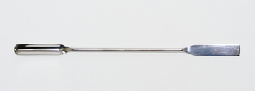 Das Bild zeigt ein langes, flaches, metallisches Werkzeug mit einem breiten Ende, das zum Mischen oder Umrühren von Substanzen verwendet wird. Es ist vermutlich für den Einsatz in Experimenten oder im Laborumfeld konzipiert.