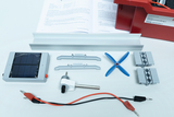 Das Bild zeigt verschiedene Komponenten eines Experimentiersets zur Energieumwandlung, darunter ein Solarpanel, eine Propellerachse und Verbindungselemente. Dazu liegt eine Anleitung zur Durchführung von Experimenten auf einem Blatt Papier.