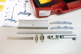 Das Bild zeigt verschiedene Komponenten eines Experimentierkastens namens "Mechanik 2.0", der für den Einsatz im Bildungsbereich gedacht ist. Neben dem Kasten sind Aufbauanleitungen sowie zahlreiche Metall- und Kunststoffteile zur Durchführung mechanischer Experimente zu sehen.