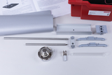 Das Bild zeigt eine Sammlung von Experimentiermaterialien, darunter Metallstäbe, Halterungen und ein Glaskolben, die für wissenschaftliche Experimente verwendet werden. Im Hintergrund befindet sich eine Informationsbroschüre, die anscheinend Anleitungen oder Details zu den Materialien enthält.