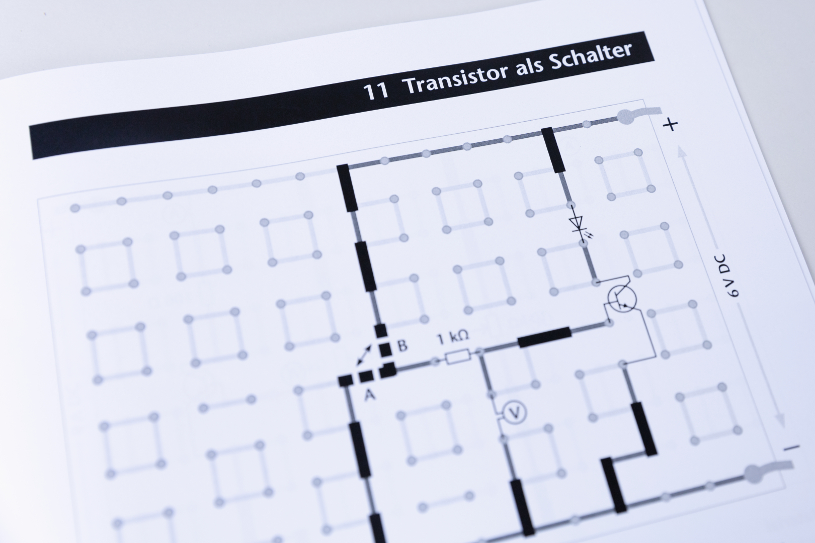 Das Bild zeigt ein Schaltbild für den Einsatz eines Transistors als Schalter, mit verschiedenen Bauteilen und Verbindungslinien. Es enthält Hinweise zu Widerstandswerten und Spannungsversorgung, die für Experimente im Bildungsbereich wichtig sind.