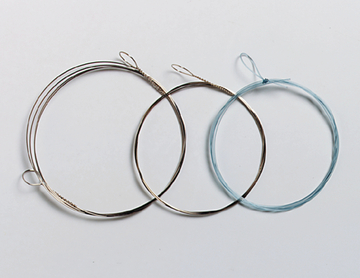 Das Bild zeigt drei verschiedene Drahtringe, die für experimentelle Zwecke im Bildungswesen verwendet werden können. Die Ringe variieren in Größe und Material, wobei einer aus blauem Draht und die anderen aus silbernem Draht bestehen.