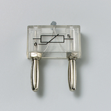 Das Bild zeigt ein transparentes Gerät mit zwei silbernen Anschlüssen und einem einfachen Schaltkreis in der Mitte. Es ist wahrscheinlich ein Experimentiergerät zur Demonstration von elektrischen oder physikalischen Prinzipien im Bildungsbereich.