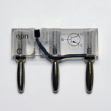 Das Bild zeigt einen NPN-Transistor in einem transparenten Gehäuse mit den Anschlüssen C (Collector), B (Base) und E (Emitter). Eine grafische Darstellung des Transistors ist eingeprägt, was seine Funktion im Experimentieraufbau verdeutlicht.