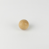 Auf dem Bild ist eine kleine, runde Holzkugel zu sehen, die auf einer weißen Fläche liegt. Sie könnte als Experimentiermaterial oder Spielzeug verwendet werden und dient möglicherweise zur Unterstützung im Bildungswesen.