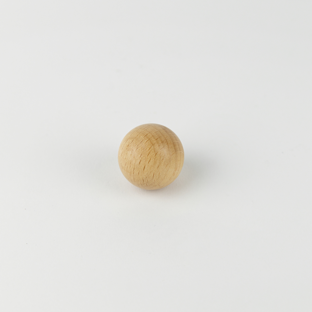 Auf dem Bild ist eine kleine, runde Holzkugel zu sehen, die auf einer weißen Fläche liegt. Sie könnte als Experimentiermaterial oder Spielzeug verwendet werden und dient möglicherweise zur Unterstützung im Bildungswesen.