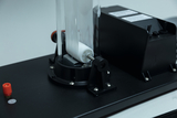 Das Bild zeigt ein Experimentiergerät mit einer transparenten Kammer und einem rotierenden Element, das offenbar für chemische oder physikalische Experimente verwendet wird. Es ist auf einer stabilen Plattform montiert und besticht durch eine technische Bauweise.