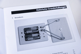 Das Bild zeigt eine Schaltung mit zwei Batterien, die auf einer Plattenbasis montiert sind. Die Drähte verbinden die Batterien mit einem weiteren Element, um den elektrischen Stromkreis zu demonstrieren.