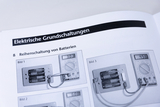 Das Bild zeigt eine Anleitung zur Reihenschaltung von Batterien, illustriert durch drei verschiedene Szenen mit eingesetzten Messgeräten. Jede Abbildung demonstriert die Spannungsergebnisse der Schaltung mit unterschiedlichen Batteriekonfigurationen.