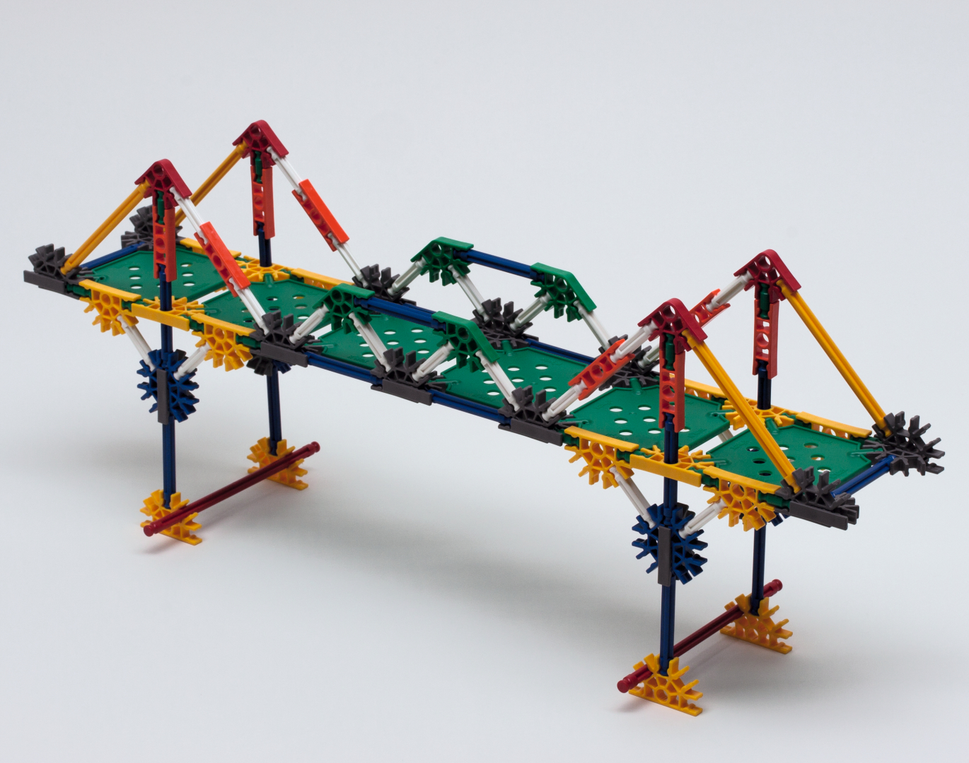 Das Bild zeigt eine Modellbrücke, die aus verschiedenen farbigen Konstruktionselementen gefertigt ist. Sie dient vermutlich zur Veranschaulichung von Ingenieurprinzipien im Bildungsbereich und fördert das praktische Lernen in Schulen.