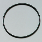 Das Bild zeigt einen schwarzen, kreisförmigen Ring, der auf einem hellen Untergrund liegt. Er könnte aus Kunststoff oder Gummi bestehen und wird möglicherweise für experimenzielle Zwecke im Bildungswesen verwendet.