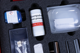 Das Bild zeigt eine Sammlung von Experimentiermaterialien in einem schaumstoffgefüllten Koffer. Zu sehen sind unter anderem eine Flasche mit Eisenpulver und ein Behälter mit Kupfersulfat, die für chemische Experimente im Bildungsbereich eingesetzt werden können.