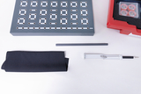 Das Bild zeigt eine Experimentierplatte mit mehreren Steckfeldern, einen grauen Stift, ein schwarzes Tuch, einen grauen Stab und eine weiße Halterung. Diese Materialien sind typisch für den Einsatz im Bildungsbereich zur Durchführung von physikalischen Experimenten.