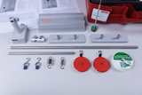 Das Bild zeigt verschiedene experimentelle Bauteile, darunter Metallstangen, Halterungen, Gewichte und Schnüre, die für mechanische Experimente verwendet werden können. Die Teile sind sorgfältig angeordnet und bieten eine Übersicht über das Experimentiermaterial für den Unterricht.