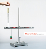 Das Bild zeigt einen massiven Hebel mit einer Balkenwaage und Gewichten zur Durchführung von Experimenten. Eine Hand hält ein Messgerät, während das System zur Veranschaulichung physikalischer Prinzipien wie das Gleichgewicht genutzt wird.