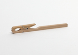 Das Bild zeigt eine Holzklammer, die in der Mitte einen metallischen Federmechanismus aufweist. Dieses einfache Hilfsmittel wird oft in Experimenten verwendet, um Objekte zusammenzuhalten oder an etwas zu befestigen.