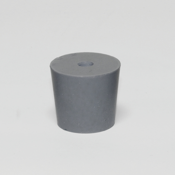 Das Bild zeigt einen grauen Zylinder aus einem festen Material, der oben eine kleine Vertiefung aufweist. Er könnte als Experimentiermaterial in einem naturwissenschaftlichen Unterricht verwendet werden.
