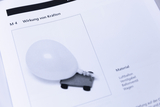Das Bild zeigt eine Abbildung in einem Lehrbuch, die das Experiment zur „Wirkung von Kräften“ beschreibt. Es sind ein Luftballon und ein Wagen abgebildet, die zur Durchführung des Experiments benötigt werden.
