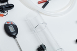 Das Bild zeigt verschiedene Laborausrüstungen, darunter ein transparentes Rohr, ein digitales Thermometer sowie Kabel mit Klemmen. Diese Materialien sind typisch für Experimentierbedarf im Bildungswesen und eignen sich für praktische Experimentierzwecke.